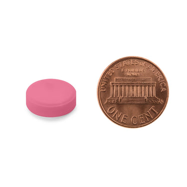 Circular pink tablet being compared to the size of a penny