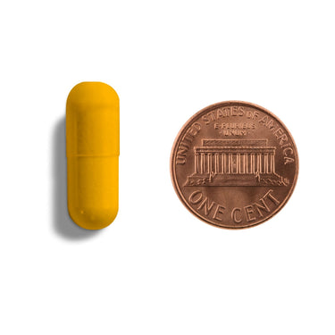 A yellow capsule being compared to the size of a penny