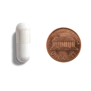A white capsule being compared to the size of a penny