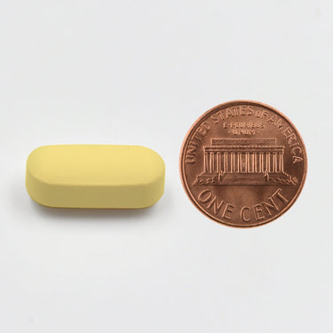 A yellow tablet being compared to the size of a penny