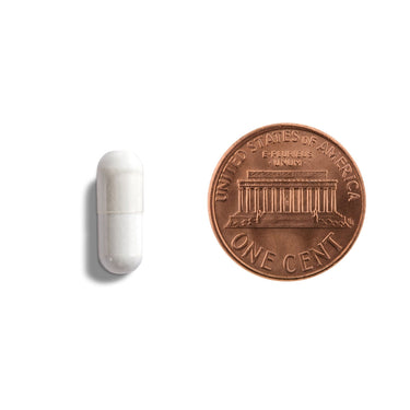 A white capsule being compared to the size of a penny