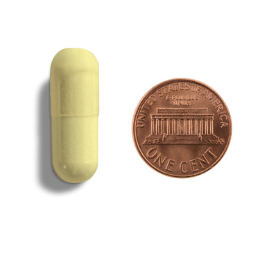A yellow capsule being compared to the size of a penny
