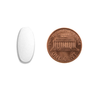 A white oval capsule being compared to the size of a penny