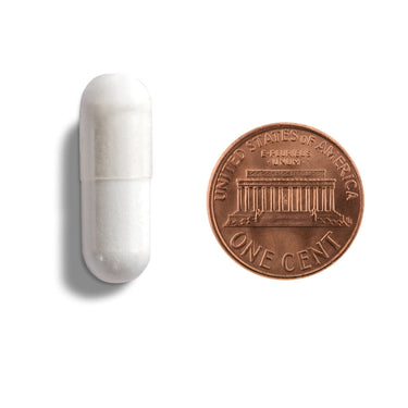 A white capsule being compared to the size of a penny