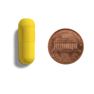A yellow capsule being compared to the size of a penny