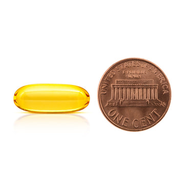 A clear yellow softgel capsule being compared to the size of a penny