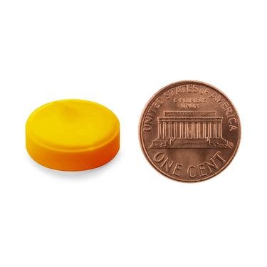 A yellow-orange tablet being compared to the size of a penny
