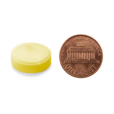 A yellow tablet being compared to the size of a penny