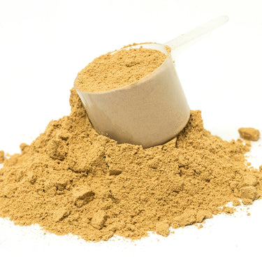 A plastic scoop filled with yellow powder in a mound of Spectra Infinite Nutrition powder