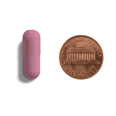 A pink capsule being compared to the size of a penny