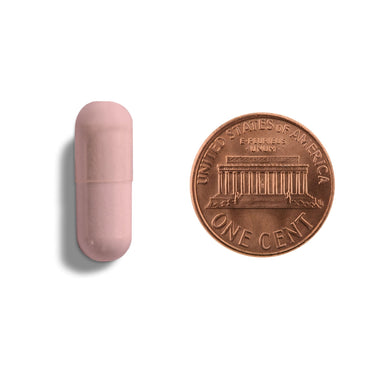A pink capsule being compared to the size of a penny