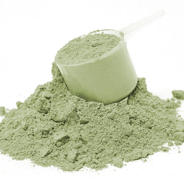 A plastic scoop filled with green powder sitting on a mound of Spectra Greens™ powder