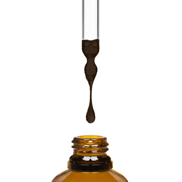 Dark liquid being dripped into an amber bottle by a dropper