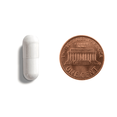 A white capsule being compared to the size of a penny