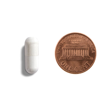 A white capsule being compared to the size of a penny