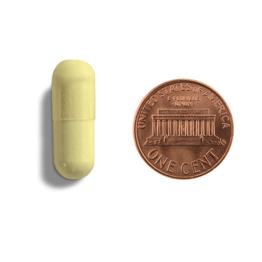 A yellow capsule being compared to the size of a penny