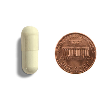 A white capsule being compared to the size of a penny