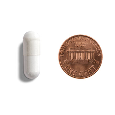 A white capsule being compared to the size of a penny
